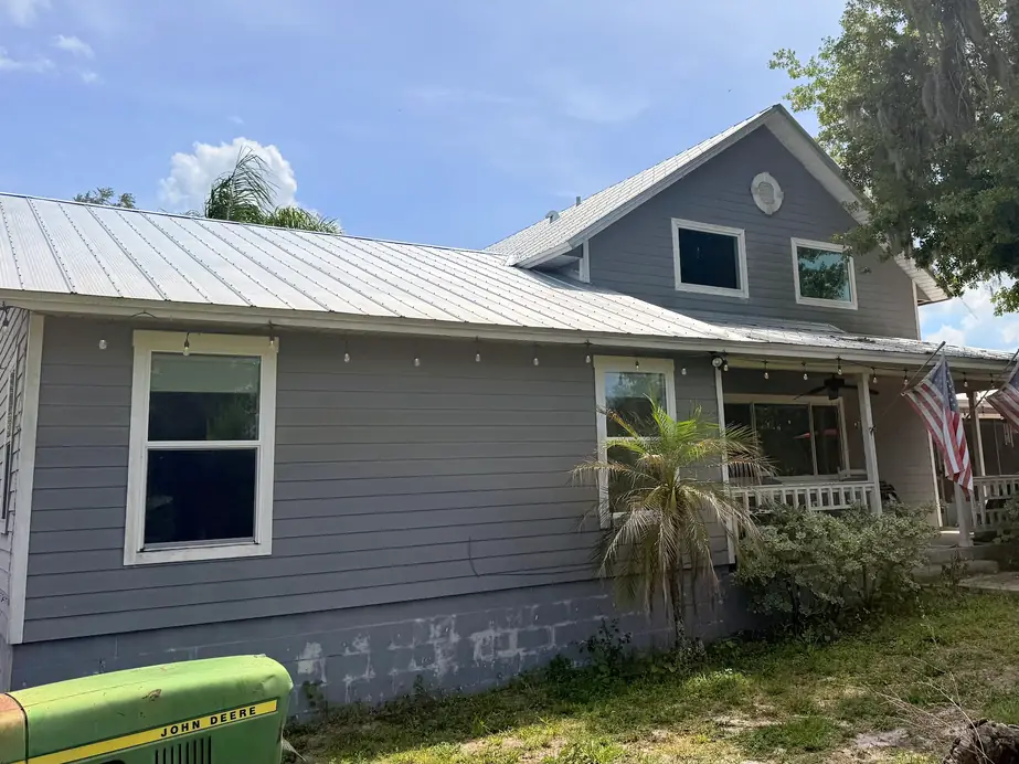 Two storey Sarasota area farmhouse with a new standing seam metal roof and a wraparound porch